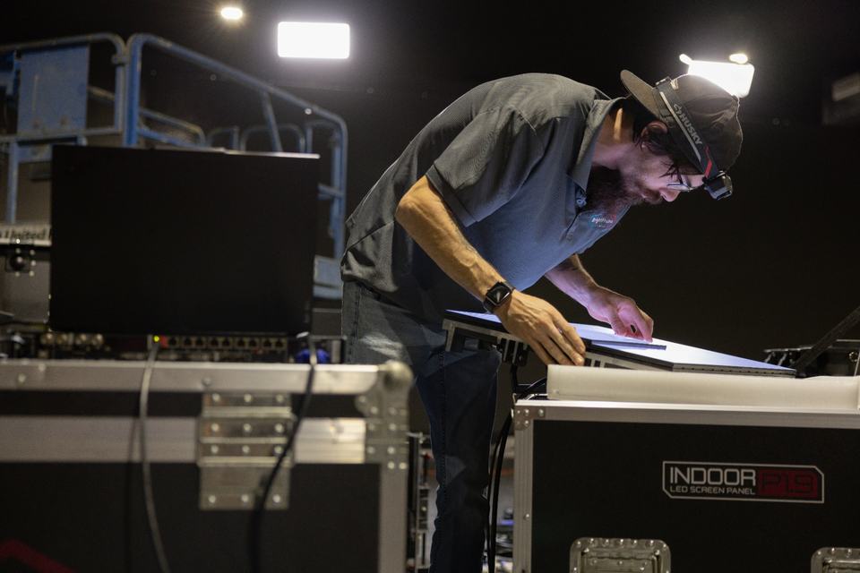 Bright Frame QC technician using a headlamp to inspect an Indoor P1.9 LED panel